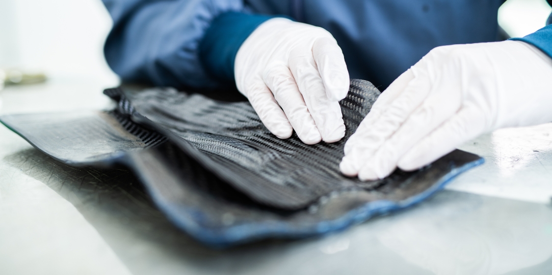 Mitarbeiter in Schutzkleidung beim Belegen von Carbonfasern für einen Carbonsattel