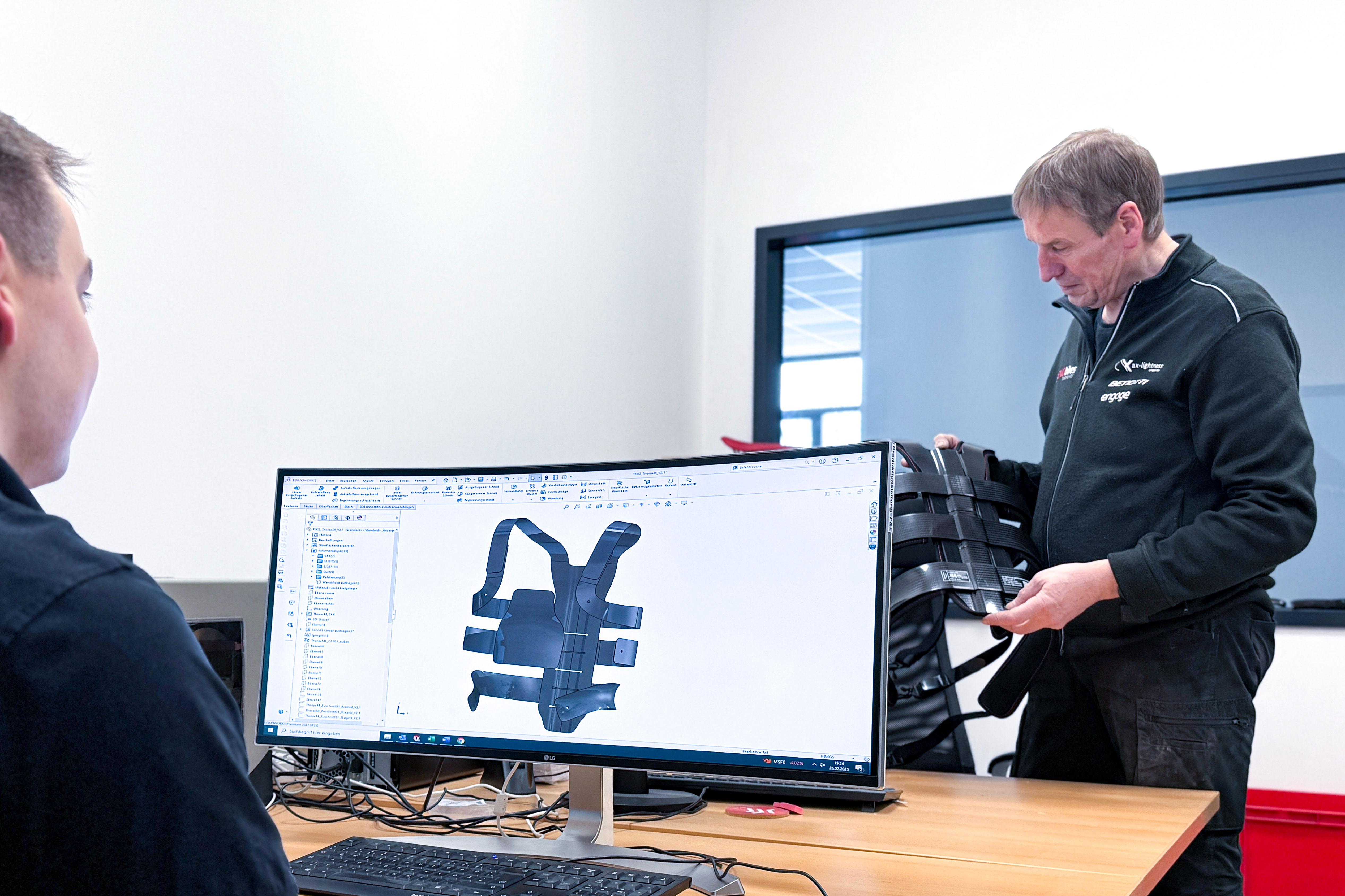 Mitarbeiter am Computer mit Thorax SSM-Layout von ax-lightness und Mitarbeiter mit Thorax SSM aus Carbon in der Hand